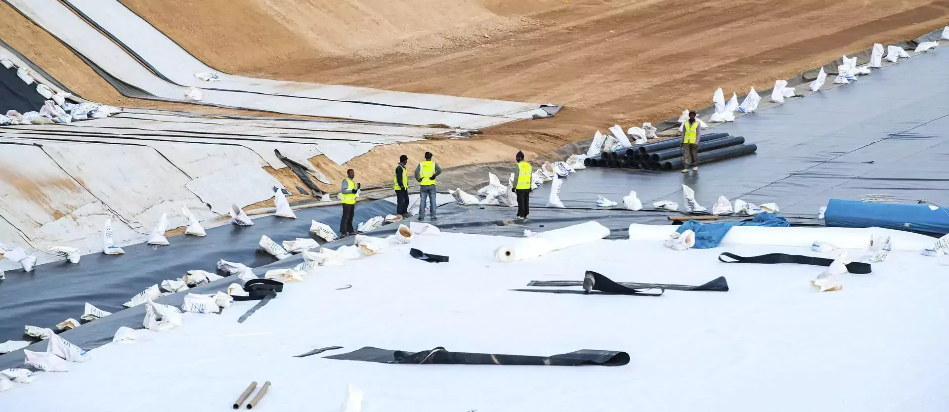 Five people working at the Ghabawi solid waste landfill site, with pipes and other building material around them